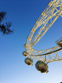 Low angle view of ferris wheel against clear blue sky