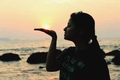 Optical illusion of woman holding sun at beach