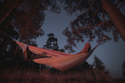 A man sleeps in a hammock on a starry night. campfire lighting. night photography