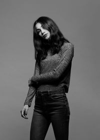 Woman wearing hat standing against gray background
