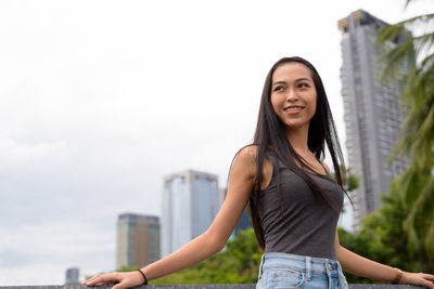 Portrait of smiling young woman standing against building