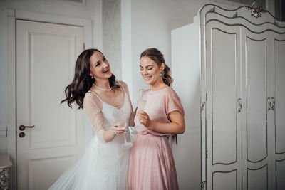 Bridesmaid and bride holding champagne flute