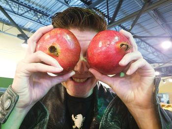 Close-up of playful woman holding pomegranates