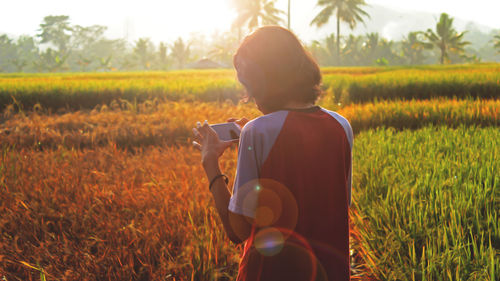 Rear view of man photographing on field