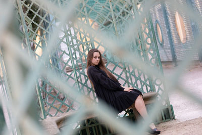 Portrait of young woman looking through fence