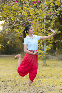 Woman standing on field against trees