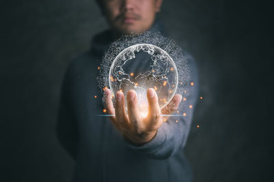 Midsection of man holding illuminated light bulb