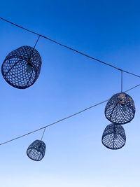 Low angle view of electric lamp hanging against blue sky