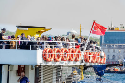 Group of people against boats at beach against sky