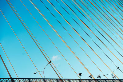 Low angle view of suspension bridge against clear blue sky