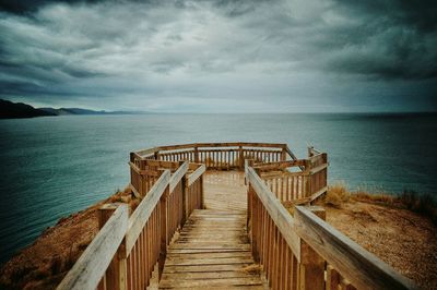 Pier on sea against cloudy sky