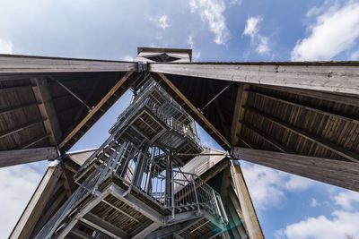 Low angle view of bridge by building against sky