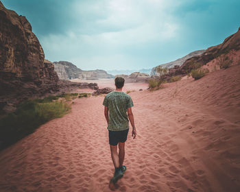 Rear view of woman walking on sand