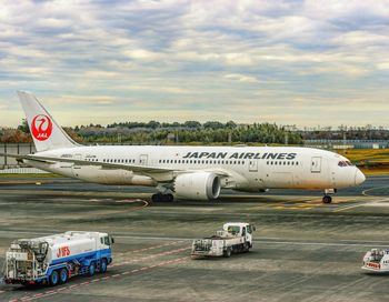 Airplane on airport runway against sky