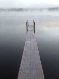 Pier over lake during foggy weather