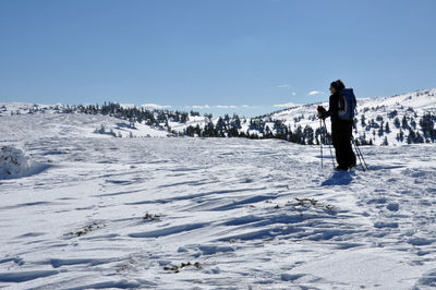 Rear view of man standing on snow covered landscape