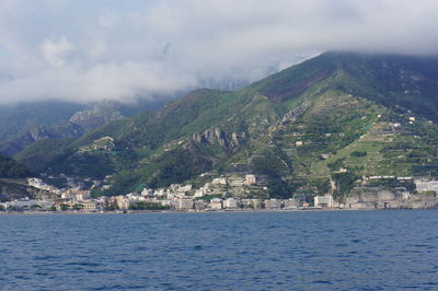 Scenic view of sea by townscape against sky