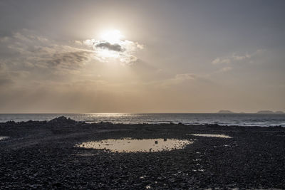Scenic view of sea against bright sun