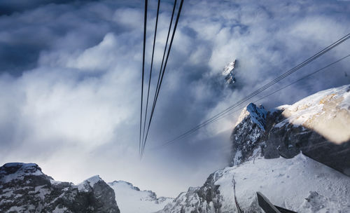 High angle view of steel cables over snowcapped mountains in foggy weather