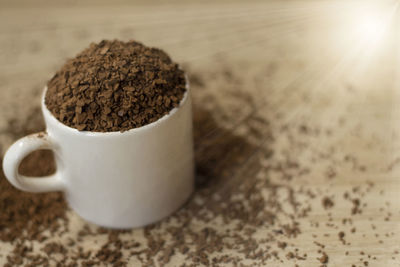 Instant soluble coffee in a white ceramic mug on a wooden floor