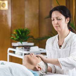 Smiling woman giving massage to client at spa