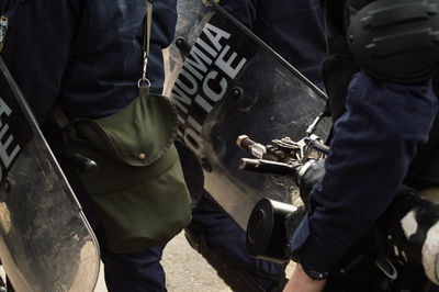 Midsection of police force with shield on road