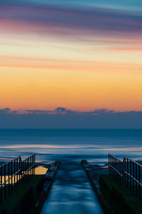 Pier over sea against sky during sunrise