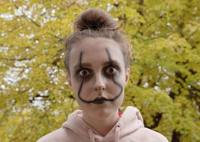 Close-up portrait of spooky teenager with halloween make-up against plants