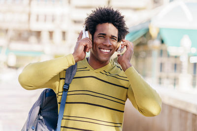 Smiling mid adult man listening music over headphones standing outdoors