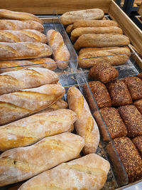 Variety of different types of bread, baguettes and hot dog buns in a bakery or grocery store