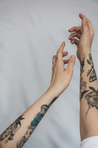 Close-up of woman's hands with tattoo against gray background