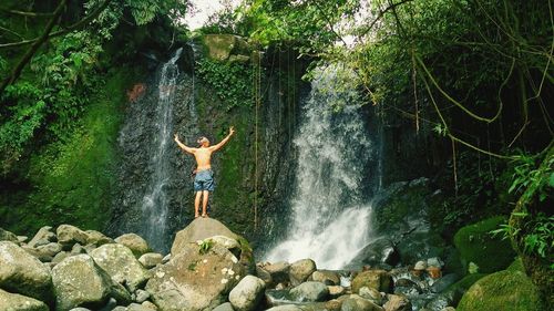 Woman standing by waterfall in forest