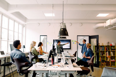 Male and female entrepreneur giving presentation to coworkers in office