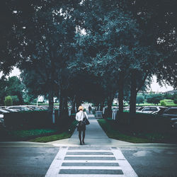 Rear view full length of woman amidst trees on footpath