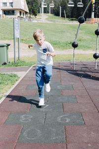 Full length of boy playing on footpath