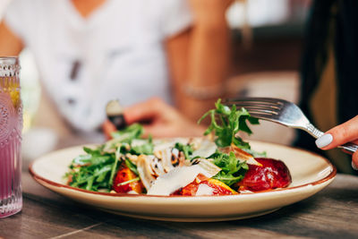Midsection of person preparing food in plate on table