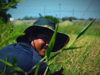 Portrait of man wearing hat while sitting on agricultural field