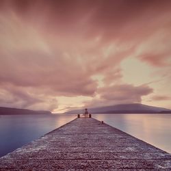 Pier on sea against cloudy sky
