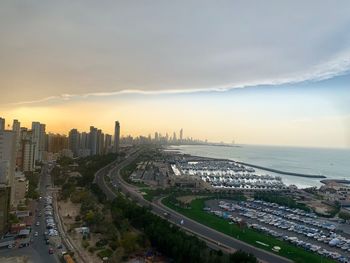 High angle view of buildings by sea against sky during sunset