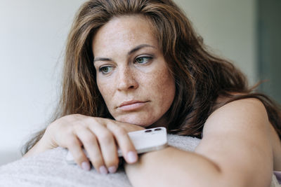 Close-up of a sad thoughtful woman holding a mobile phone.