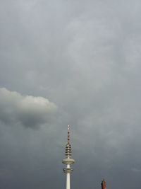 Low angle view of communications tower against cloudy sky