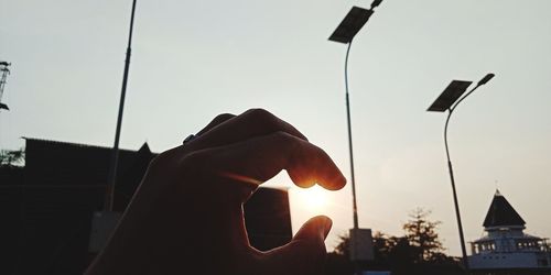 Person holding umbrella against sky during sunset