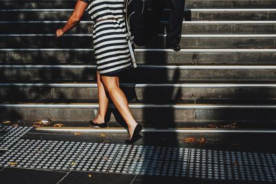 Low section of woman wearing striped dress walking on stairs