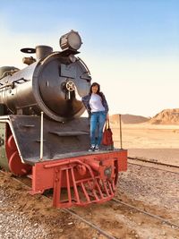 Portrait of smiling woman standing on steam train at desert
