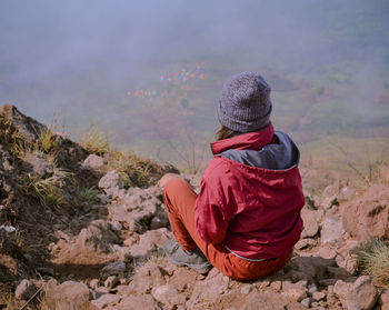 Rear view of woman sitting on rock