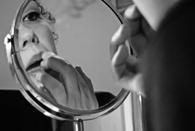 Reflection of woman applying cream on lips in mirror