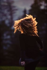 Rear view of woman standing against trees