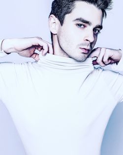 Portrait of young man making face over white background