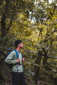 Side view of young man looking away in forest