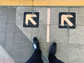 Low section of man standing on arrow sign